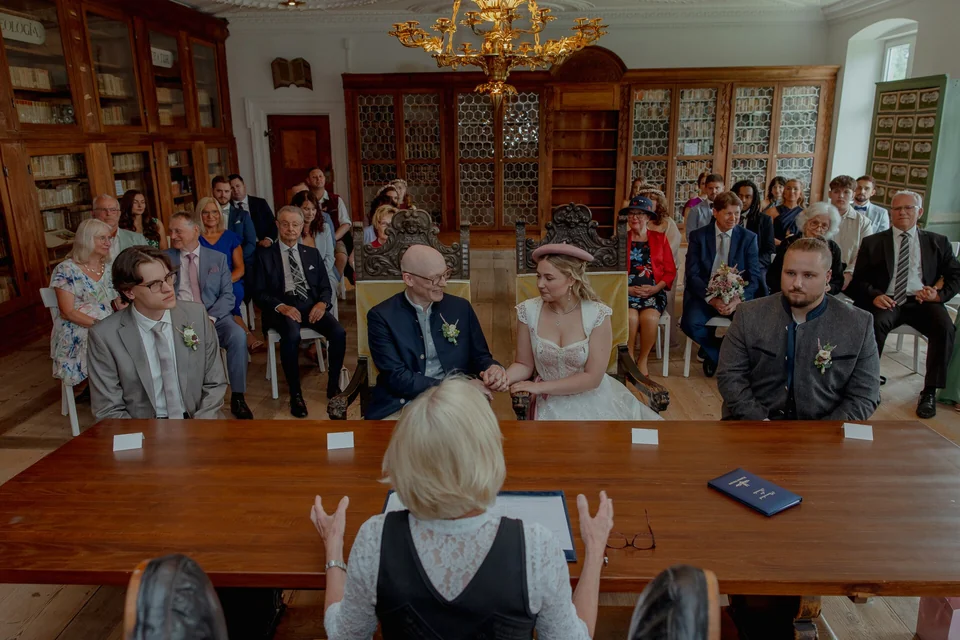 Standesamtliche Trauung in der Bibliothek im Kloster Holzen, Brautpaar sitzt vor der Standesbeamtin und hält sich an den Händen, emotionale Hochzeit im historischen Ambiente