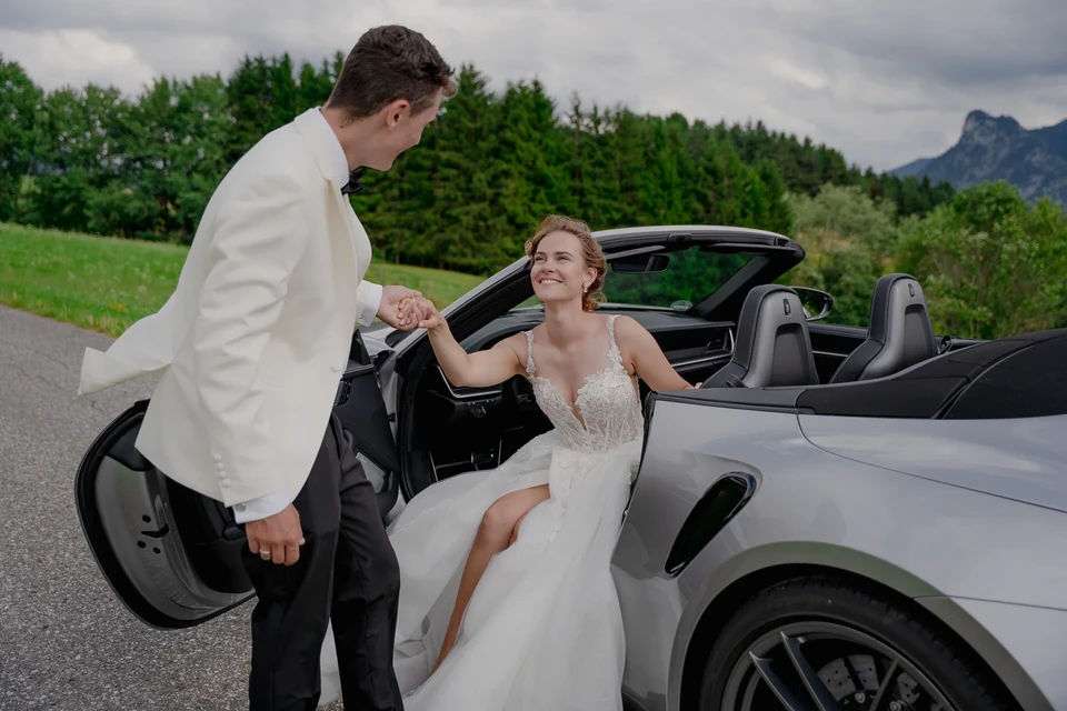 Bräutigam hilft der Braut aus dem Porsche Cabrio – Hochzeitsfotograf René Cerny